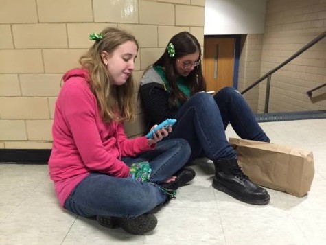 Juniors Meghan Westefer and Skylar Forrest check their phones for a moment while they eat a snack during one of their breaks.