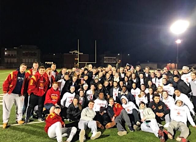 Football players and participants of the Powder Puff Game pose on the turf.  