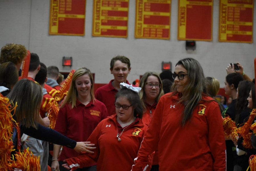 Pictured from left to right are Sarah Goeckel, David Gibson, Molly Warren, Annie Gable, and Meaghan Hennessy entering the Juenger Gymnasium while being cheered on by football players and cheerleaders.  