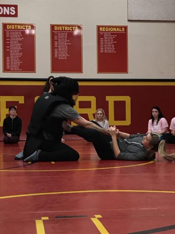 Senior Pamela Cobaugh (right) practices her grip and kicks against the defense trainer.