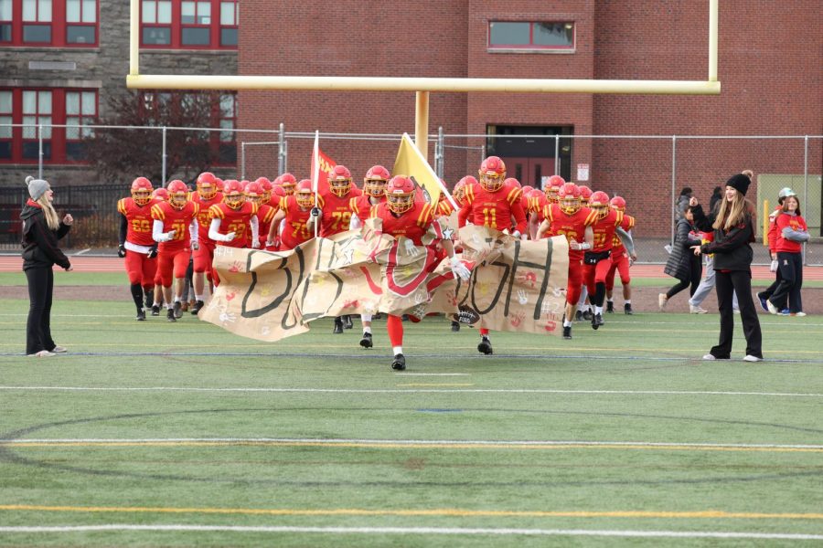 The Haverford football team bursts through a banner, proudly displaying the Fords mantra, Built Ford Tough.