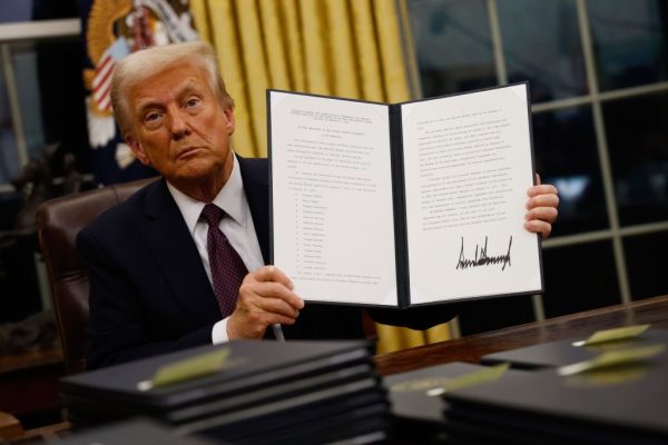 President Trump holds up a signed executive order in the Oval Office.