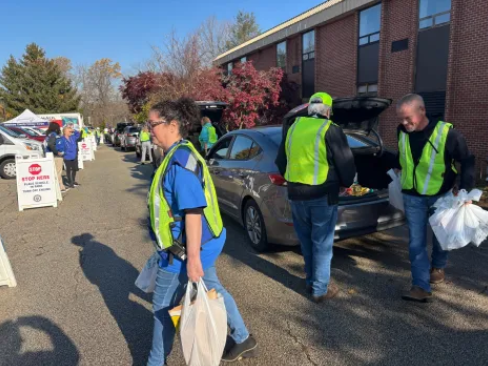 Volunteers helping unload food from cars for a Delco Community food drive (Delco Times).
